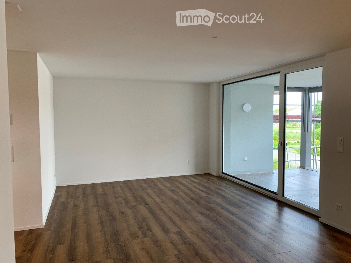 Empty room with wooden flooring, white walls, and large sliding glass doors leading to a patio.