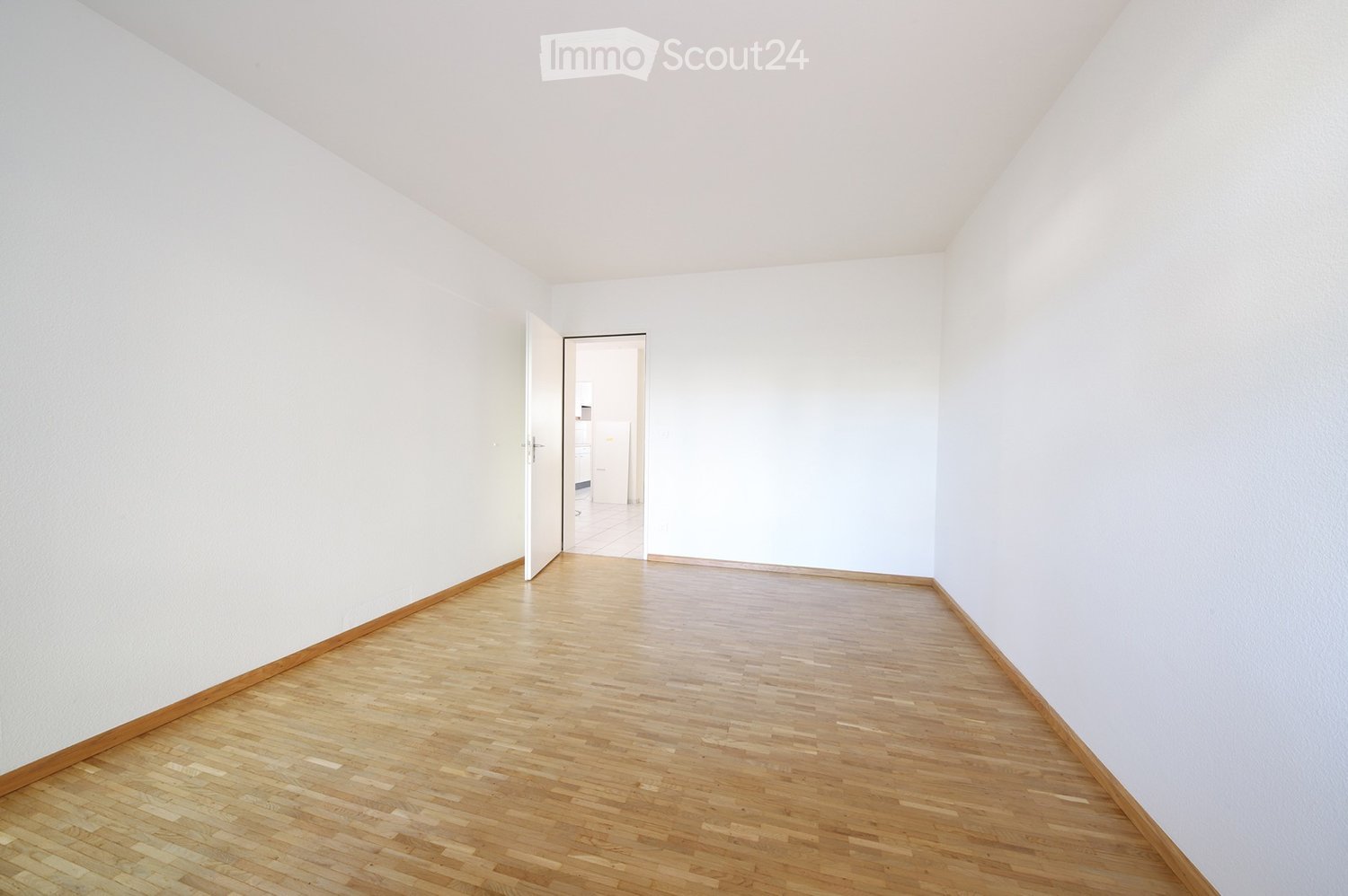 Completely empty room with bare white walls and wooden floor. No furniture or equipment.