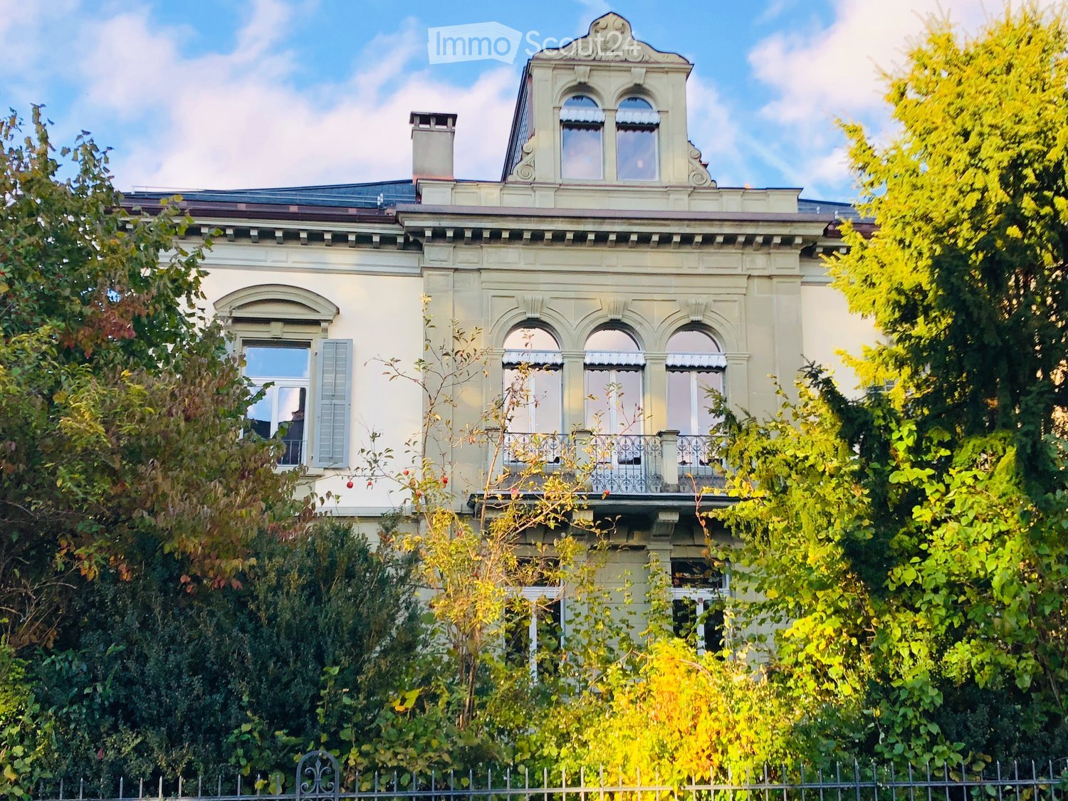 3 story house, white exterior, multiple windows, balcony, chimney, surrounded by trees