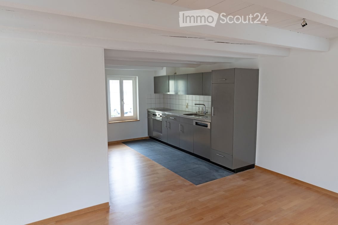 Modern kitchen with grey cabinets, stainless steel appliances, and wooden flooring.