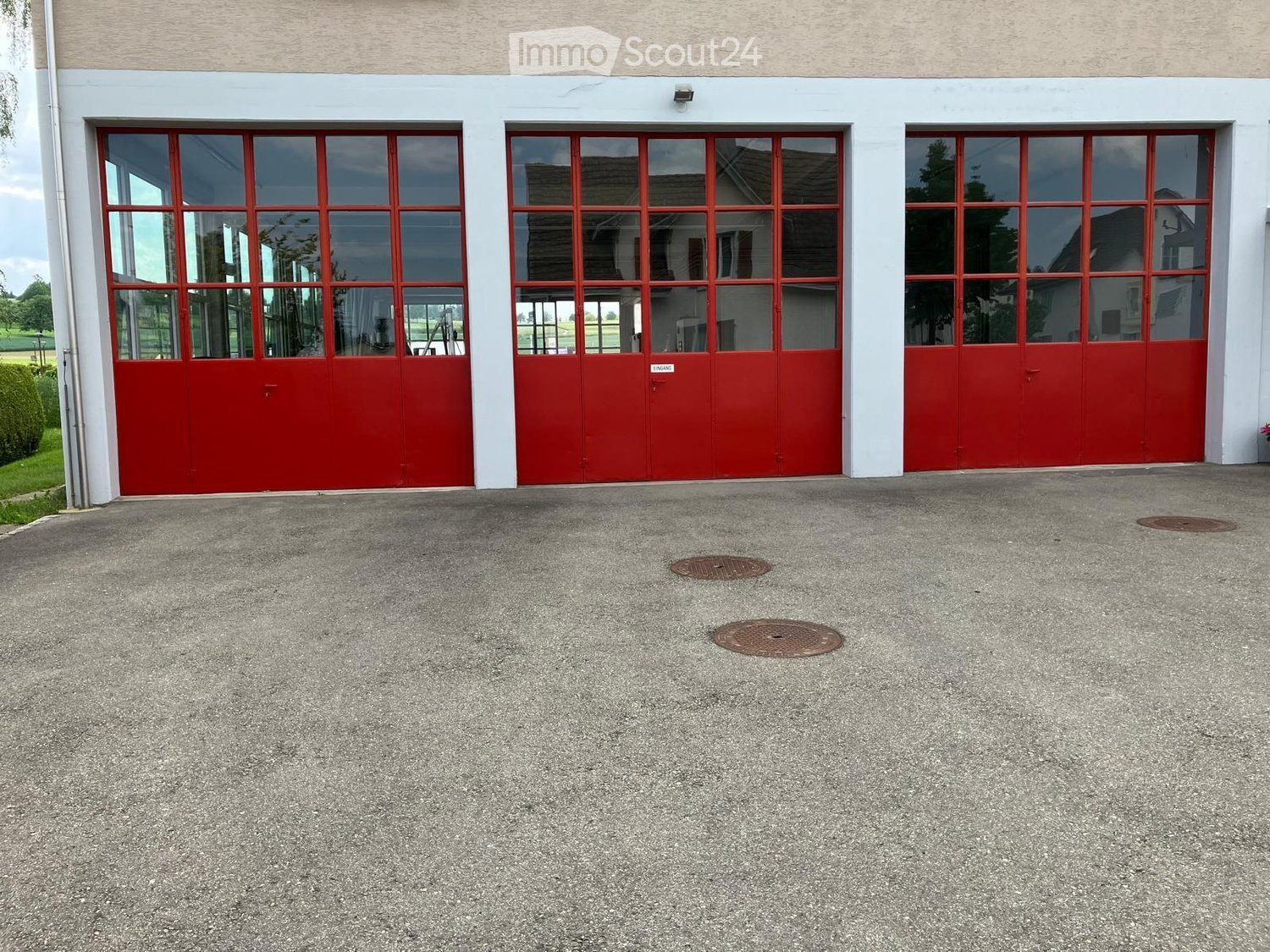 Building with three large red garage doors and a concrete driveway.