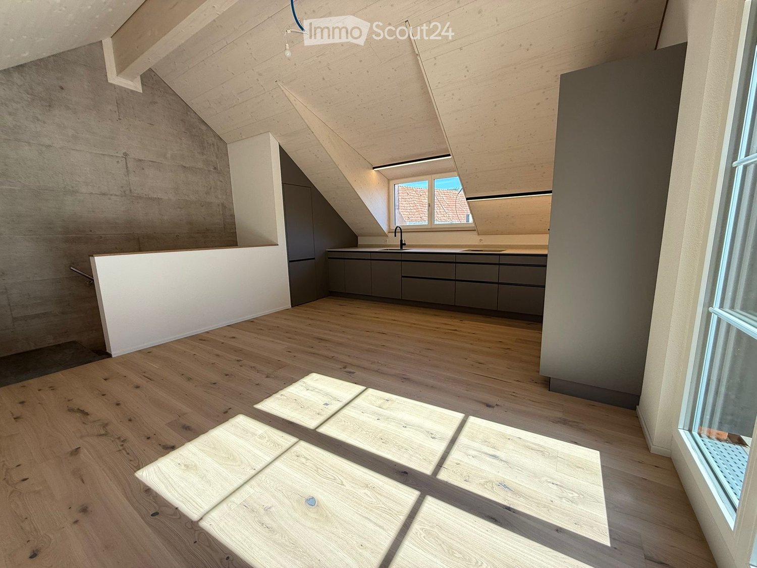 Empty attic space with wooden flooring, exposed wooden beams, and built-in cabinets. Features large windows and a modern design.