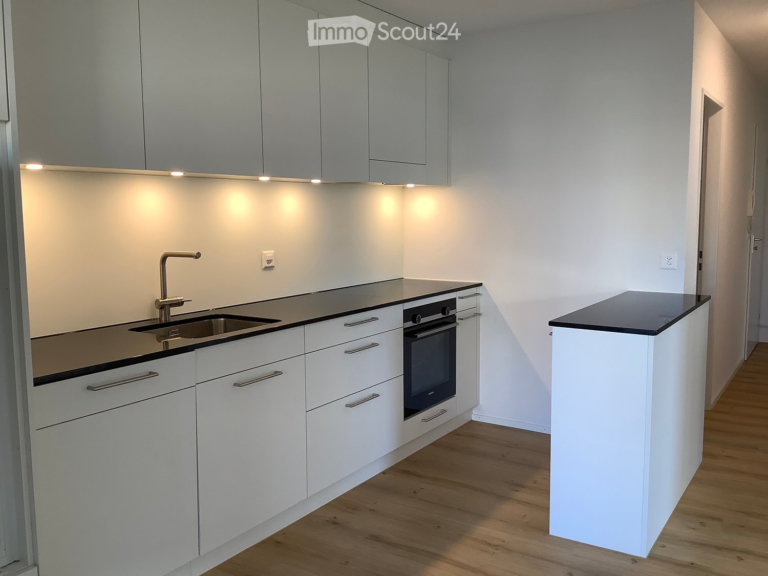 modern kitchen with white cabinets, black countertop, integrated dishwasher, sink with faucet, built-in oven
