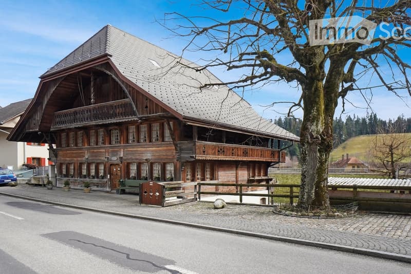 2 story wooden house, gray roof, wooden balcony, multiple windows, wooden fence, tree