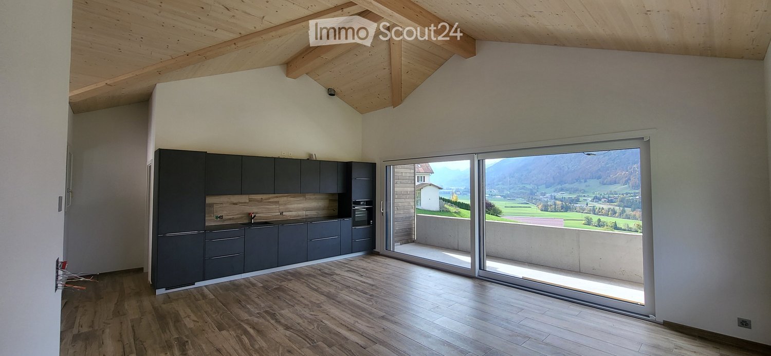Modern kitchen with dark grey cabinets, wooden countertops, and a large sliding glass door offering a scenic mountain view.
