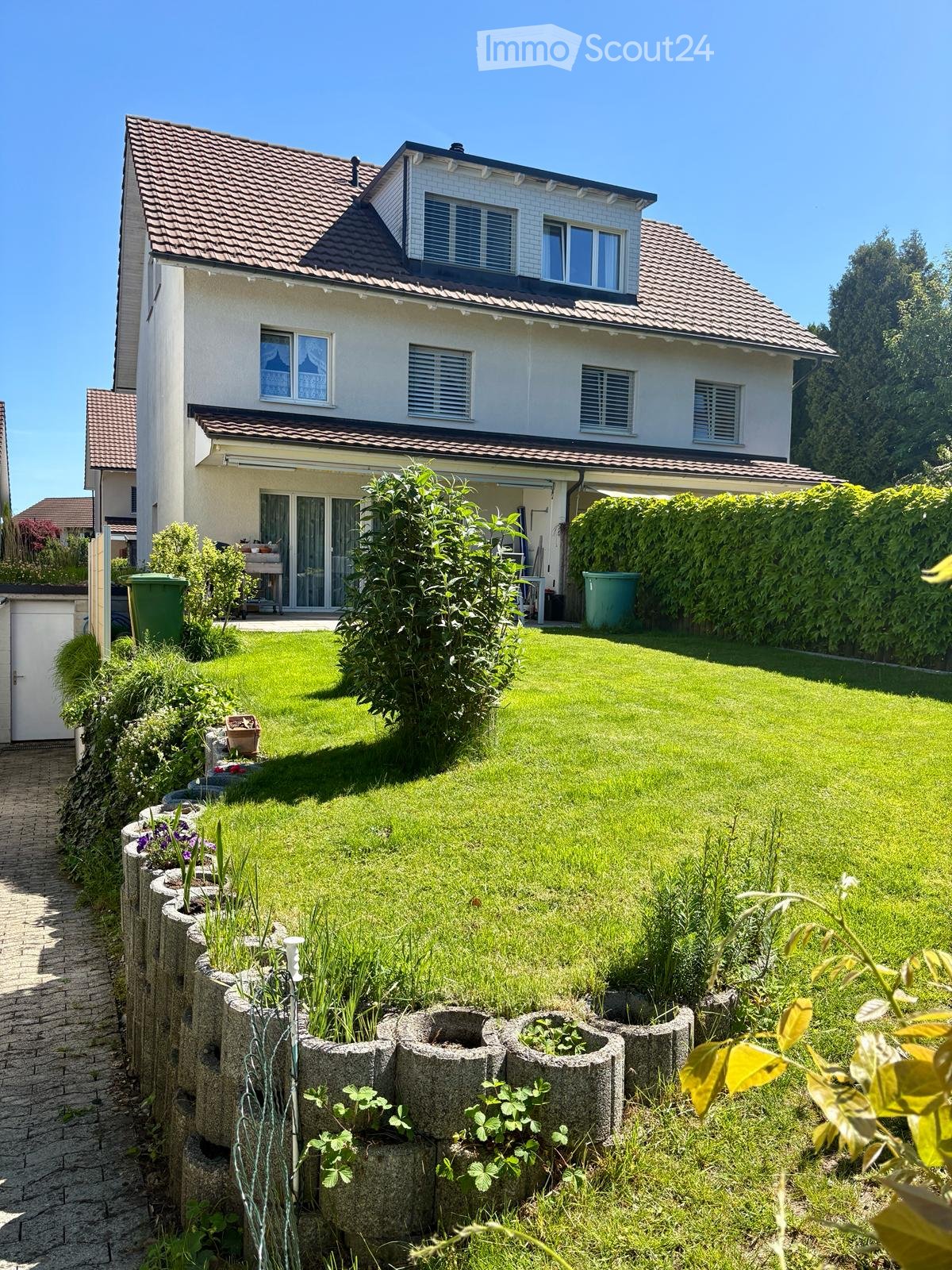 Well-maintained garden with a lawn, flower beds, and a stone pathway leading to the house.