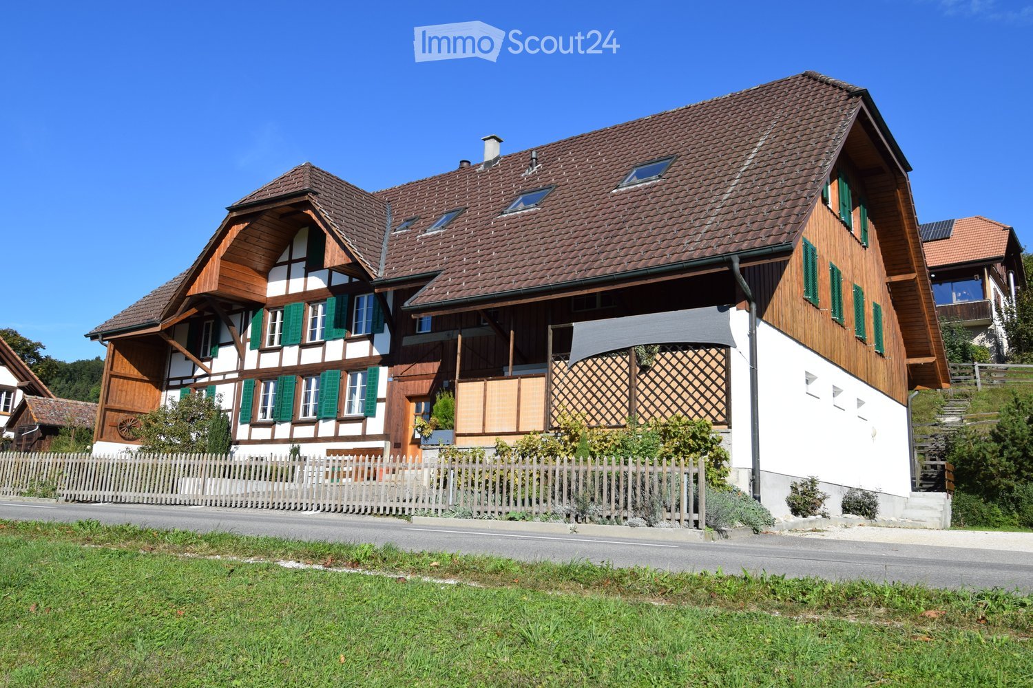 2 story house, brown roof, green shutters, wooden exterior, white walls, wooden fence, garden