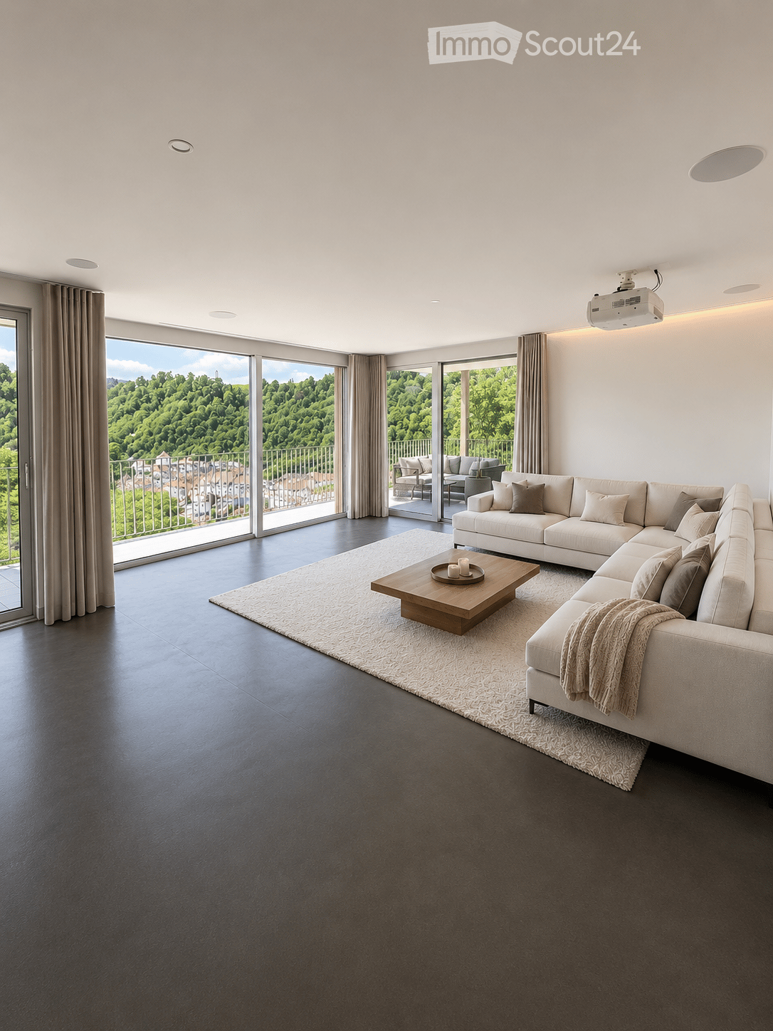 Modern living room with large windows offering a scenic view, featuring a white sectional sofa, wooden coffee table, and projector mounted on the wall.