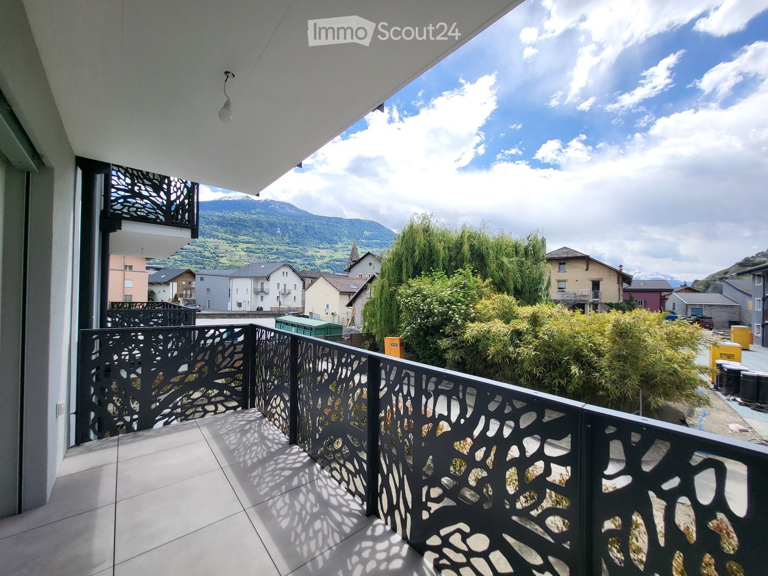 Balcony with modern black metal railing, tiled floor, and scenic mountain view.
