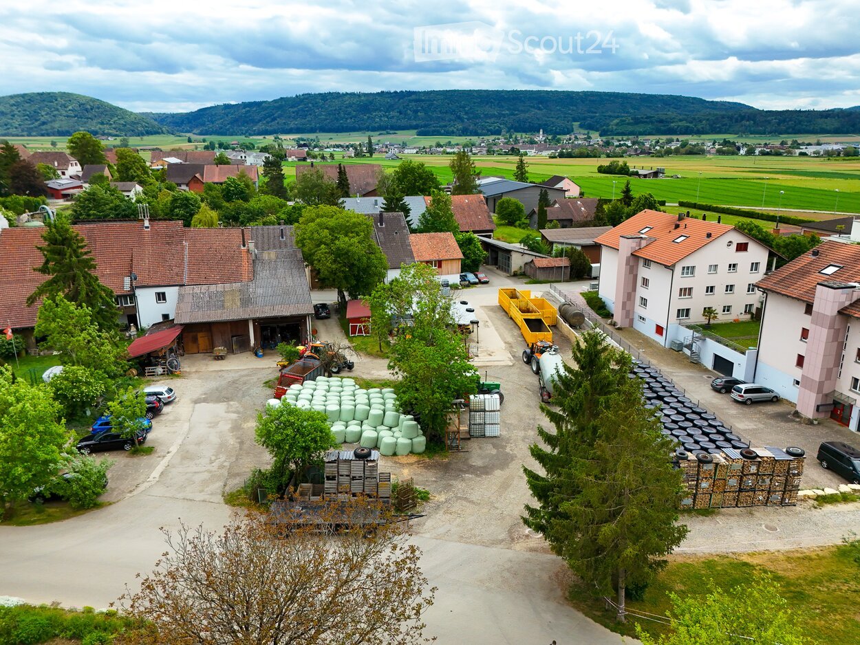 Aerial view of a rural farm complex with multiple buildings, parking areas, and agricultural equipment.