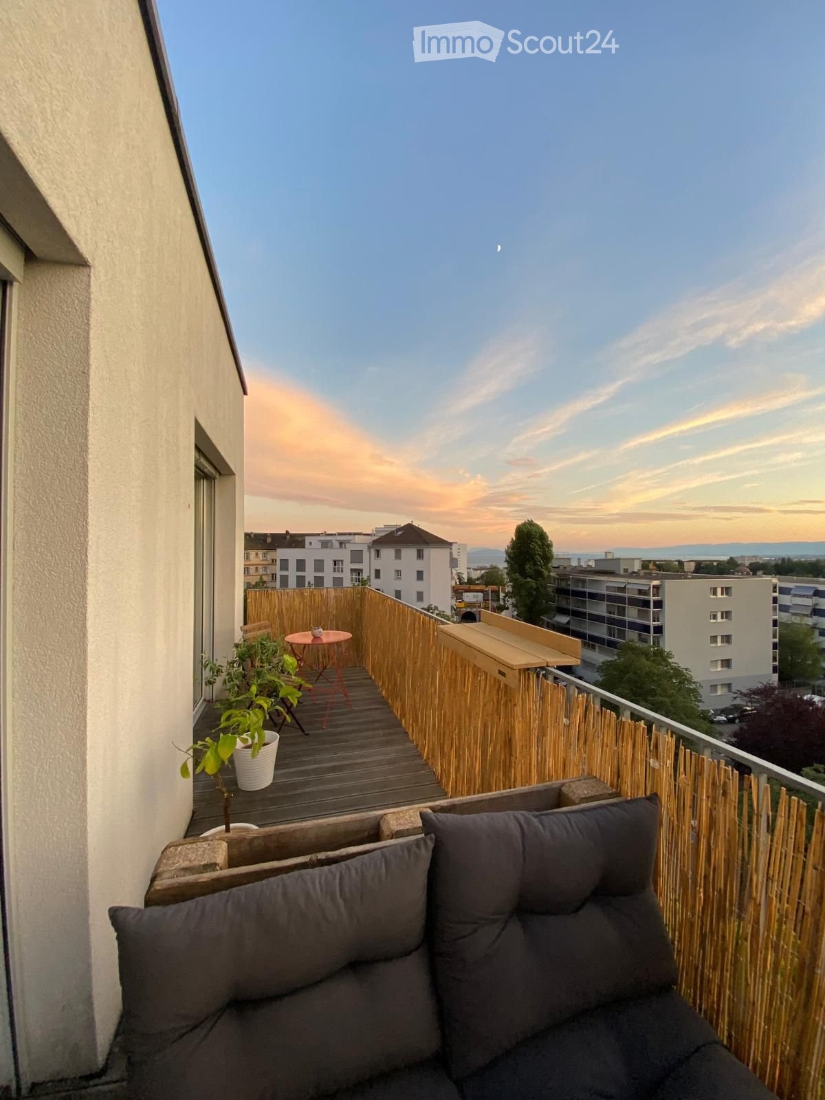 Balcony / Terrace. Balcony with wooden decking, bamboo privacy screen, grey sofa, small round table, and potted plants.
