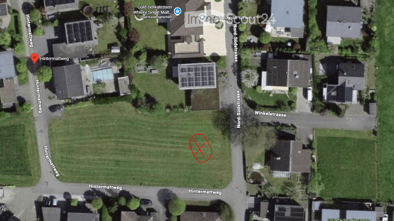 Aerial view of a residential area with multiple houses, green spaces, and a swimming pool visible in one of the yards.