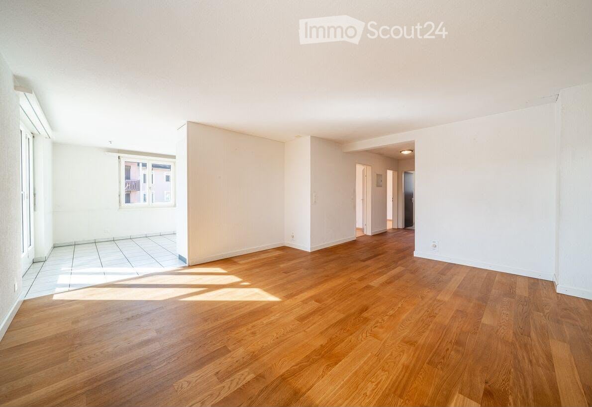 Unfurnished Room. Empty room with wooden flooring and white walls, featuring a large window and an open doorway leading to another room.