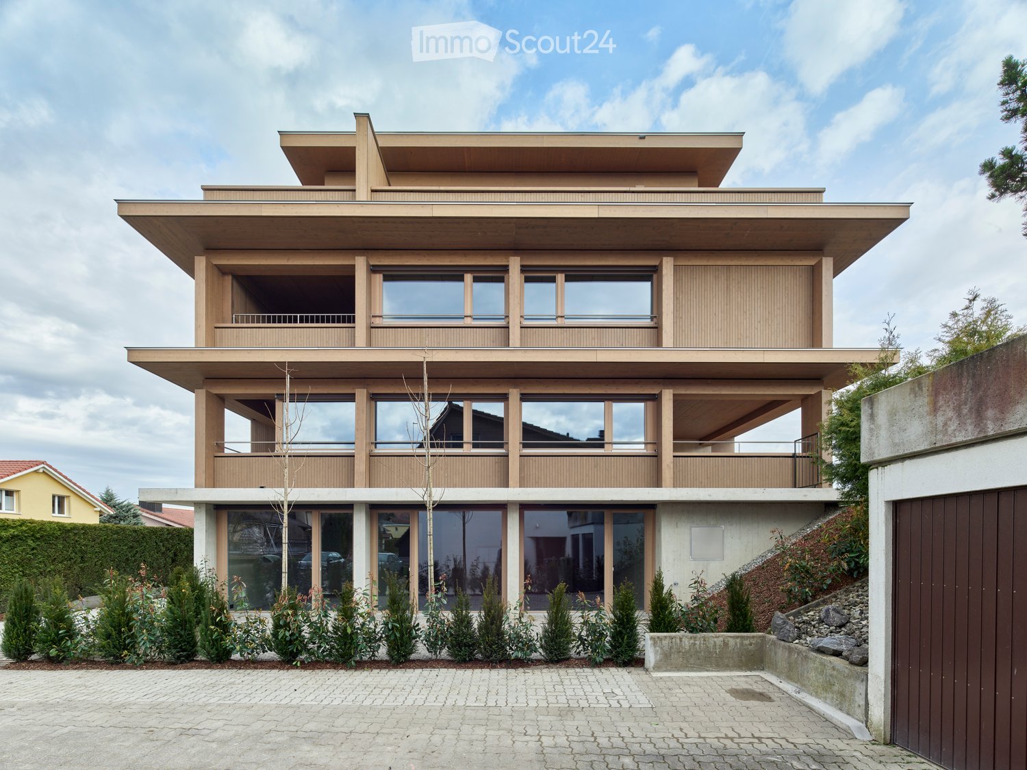 House. Modern multi-story house with wooden exterior, large windows, and a driveway.