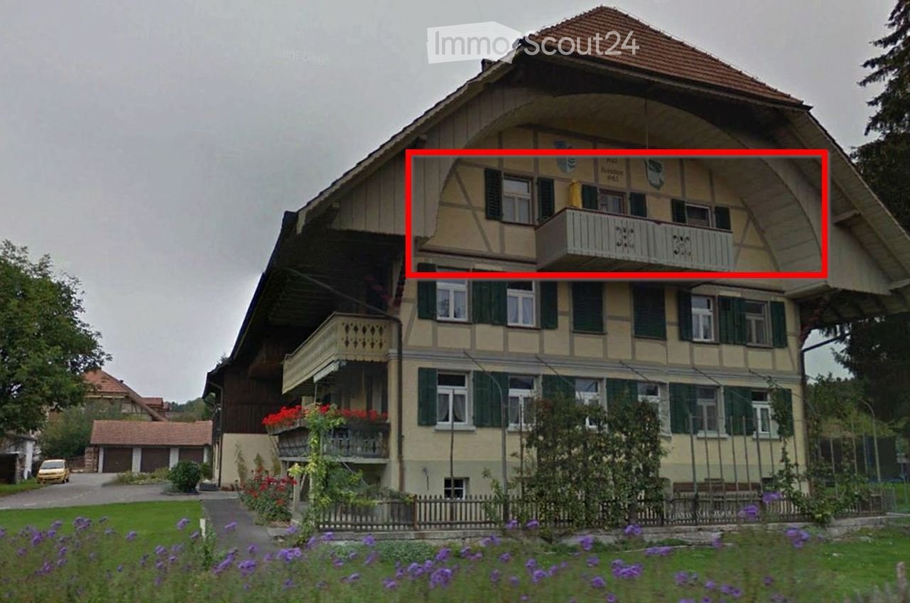 Two-story traditional house with a pitched roof, multiple balconies, green shutters, and a well-maintained garden.