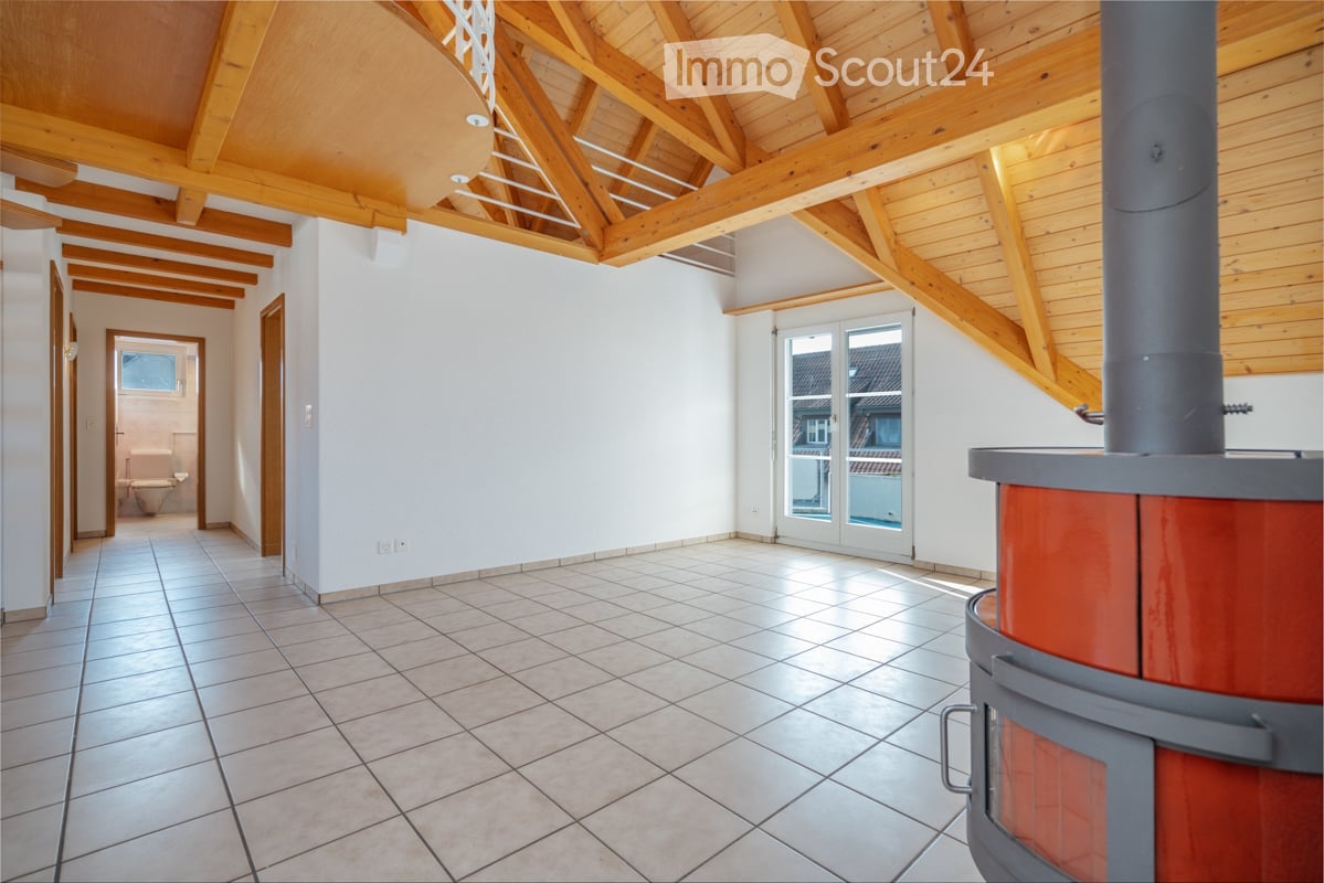 Bright hallway with wooden beams, tiled floor, and a visible fireplace. A bathroom is visible in the background.