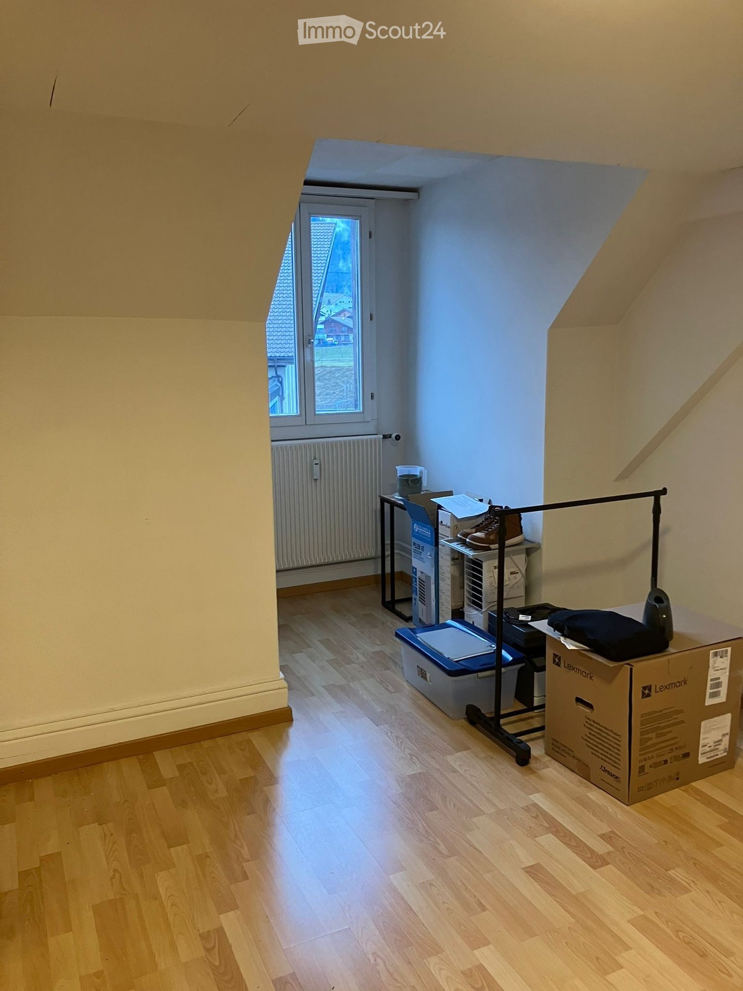 empty room, wooden floor, white walls, window, radiator, boxes, storage boxes, shoes, clothes
