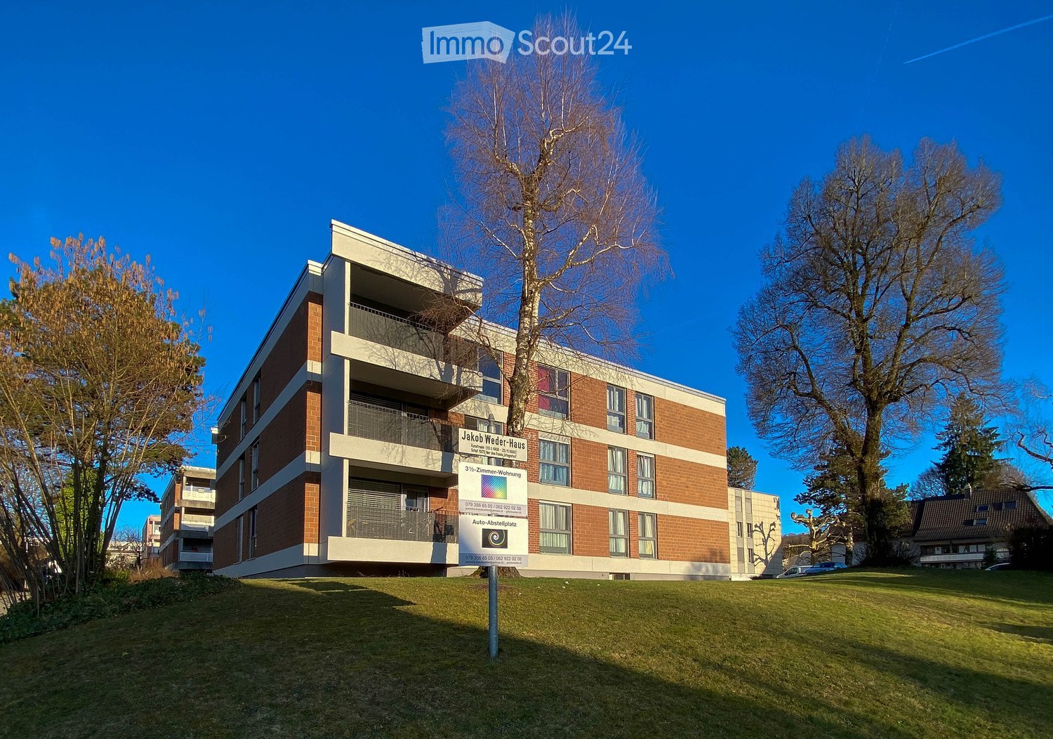 3-story apartment building, brick exterior, balconies, signboard in front