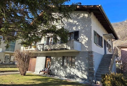Two-story house with a balcony, garage, and steps leading to the entrance.
