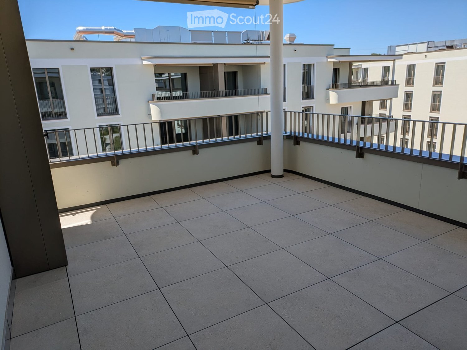 Balcony with tiled floor, metal railing, and view of neighboring buildings.