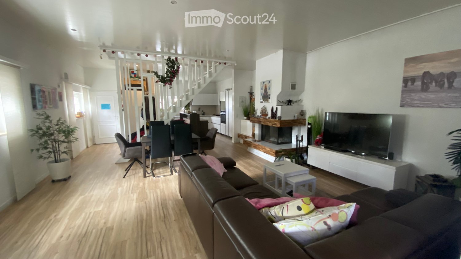 wooden floor, fireplace, brown sofa, dining table, TV, potted plants