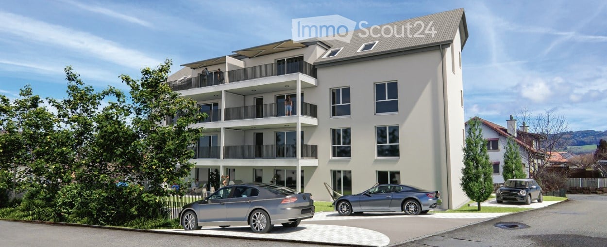 Modern multi-story residential building with balconies, large windows, and several parked cars in front.