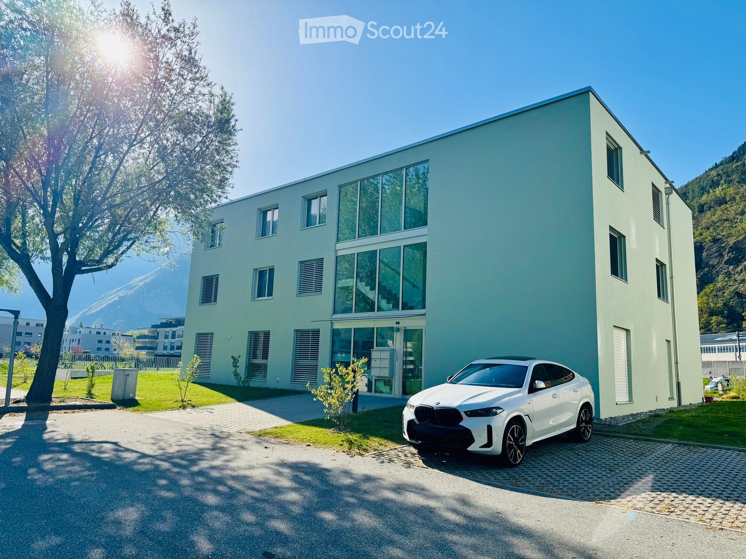 Modern building with large windows and a white car parked in front.