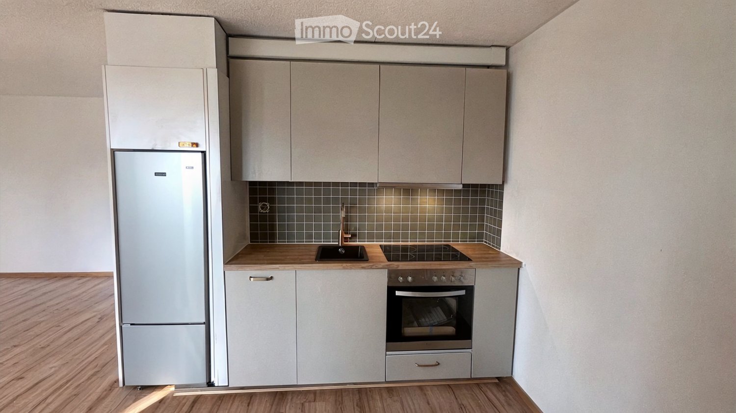 Modern kitchen with light-colored cabinets, stainless steel appliances, and wooden countertops.