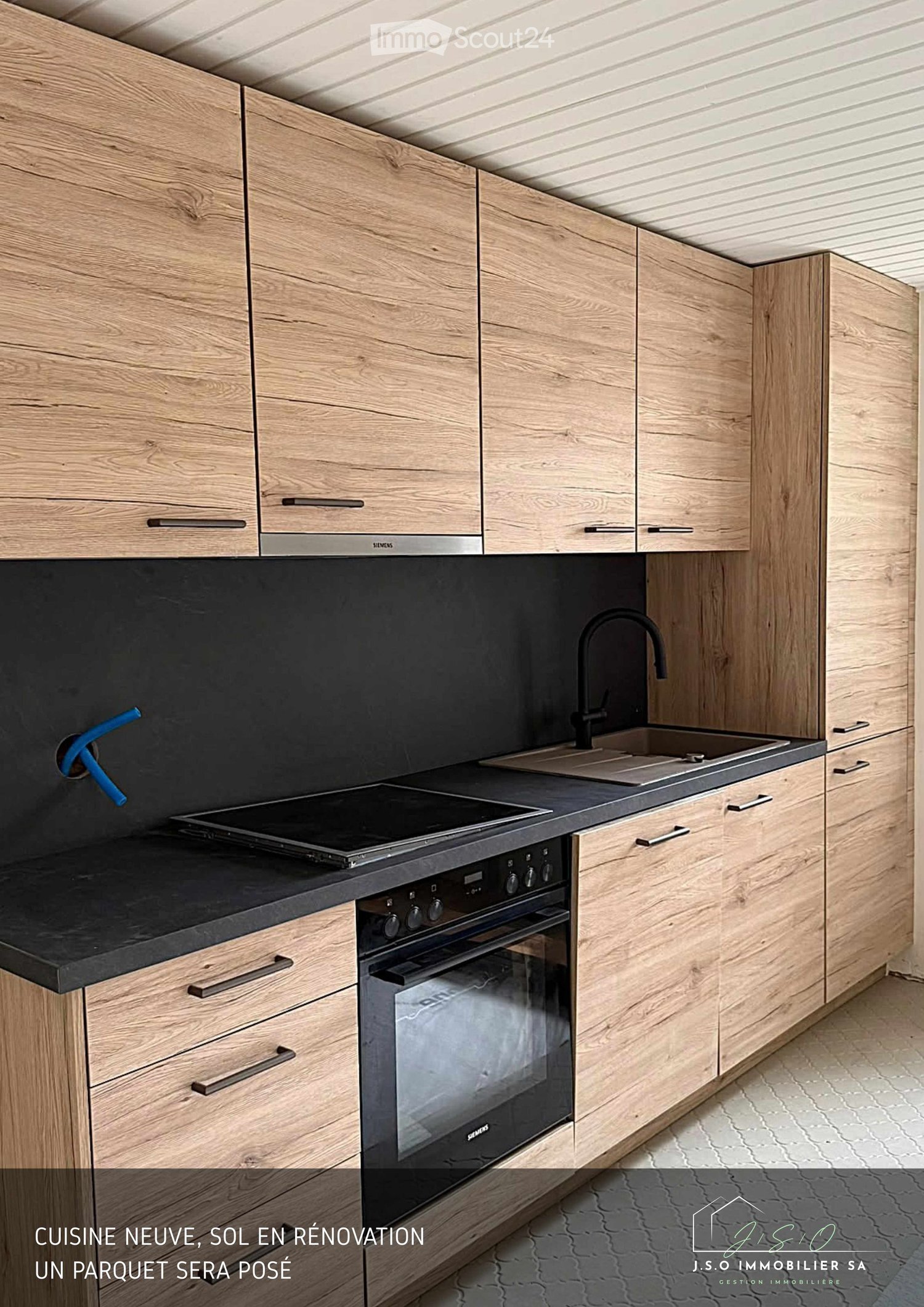 Modern kitchen with light wooden cabinets, stainless steel appliances, black countertop, and a sink with a modern faucet.