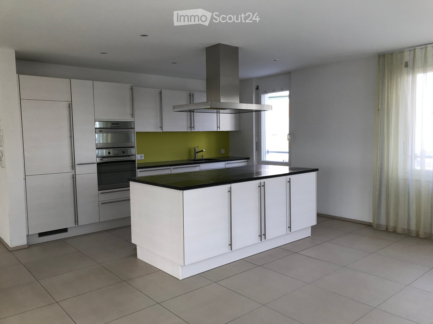 Modern kitchen with white cabinetry, central island, stainless steel oven, range hood, and sink.
