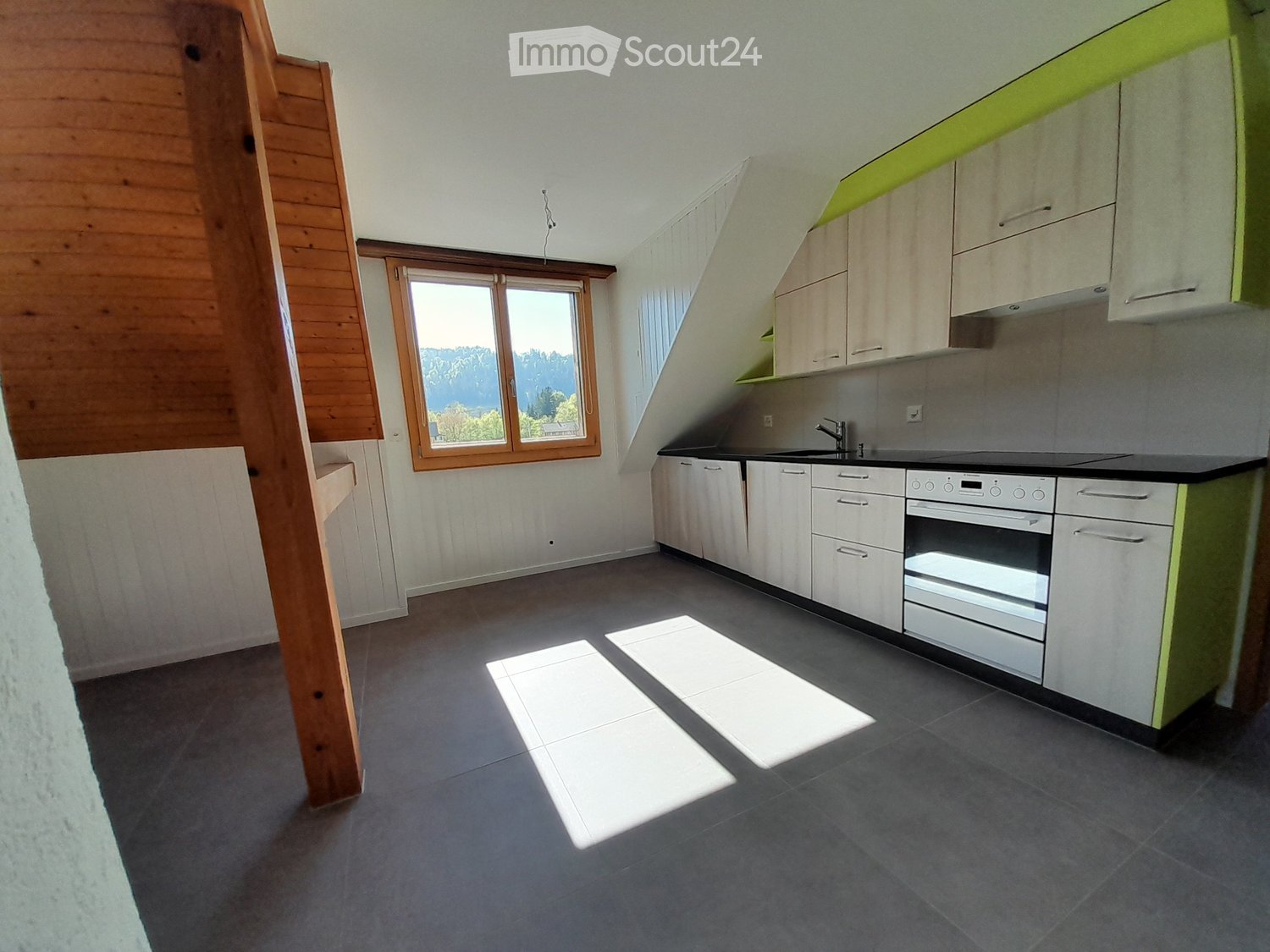 Modern kitchen with white cabinets, stainless steel appliances, and a large window offering a scenic view.