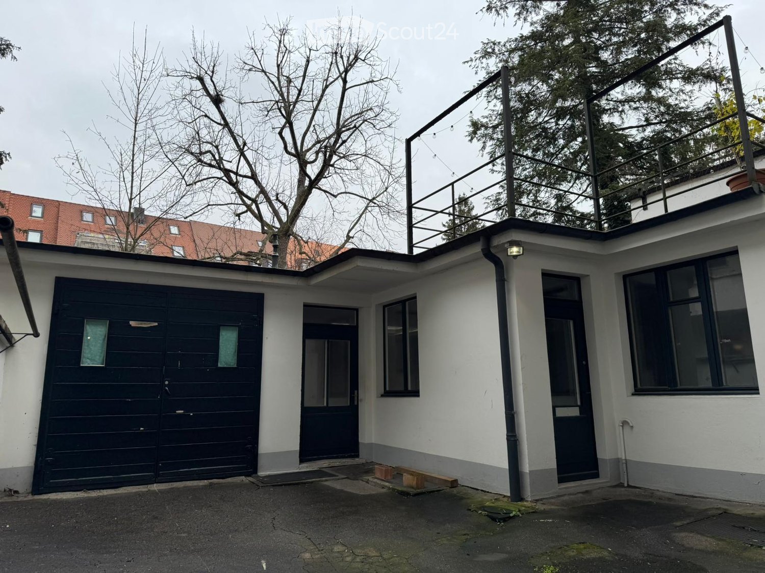 White house with garage, terrace on the top, black railings, black windows