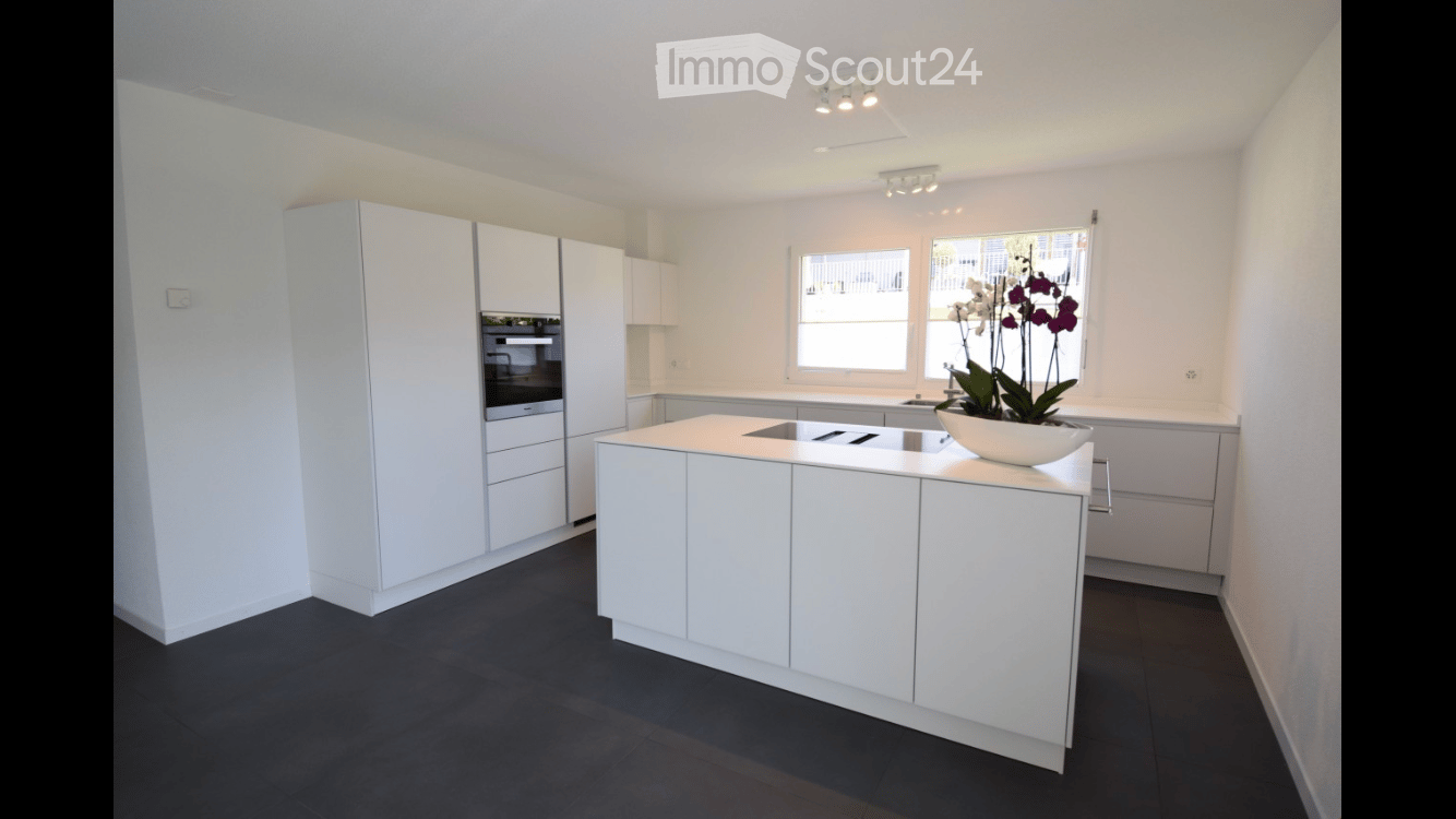 Modern kitchen with white cabinets, central island, and dark flooring.