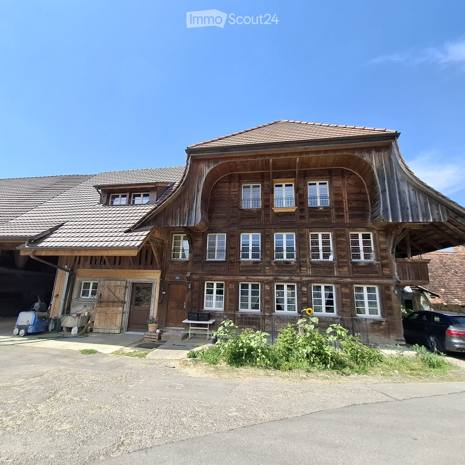 Traditional wooden house with multiple windows, garage, and small garden area.