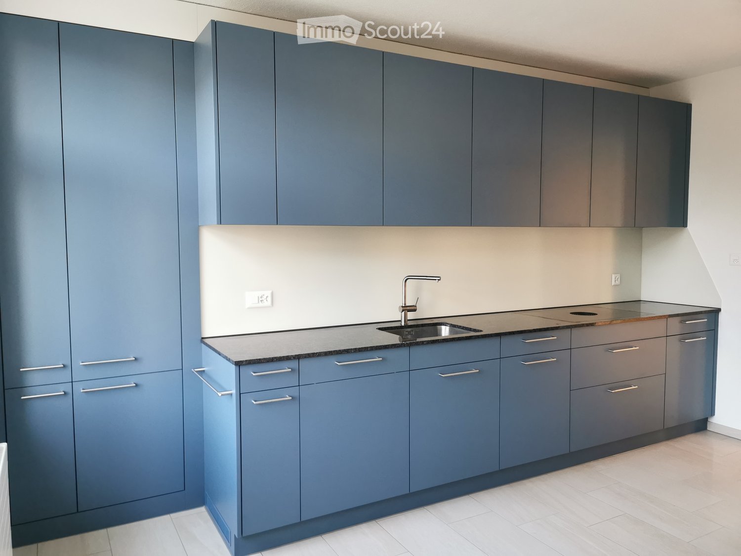 Modern kitchen with blue cabinets, stainless steel sink, and sleek countertops.