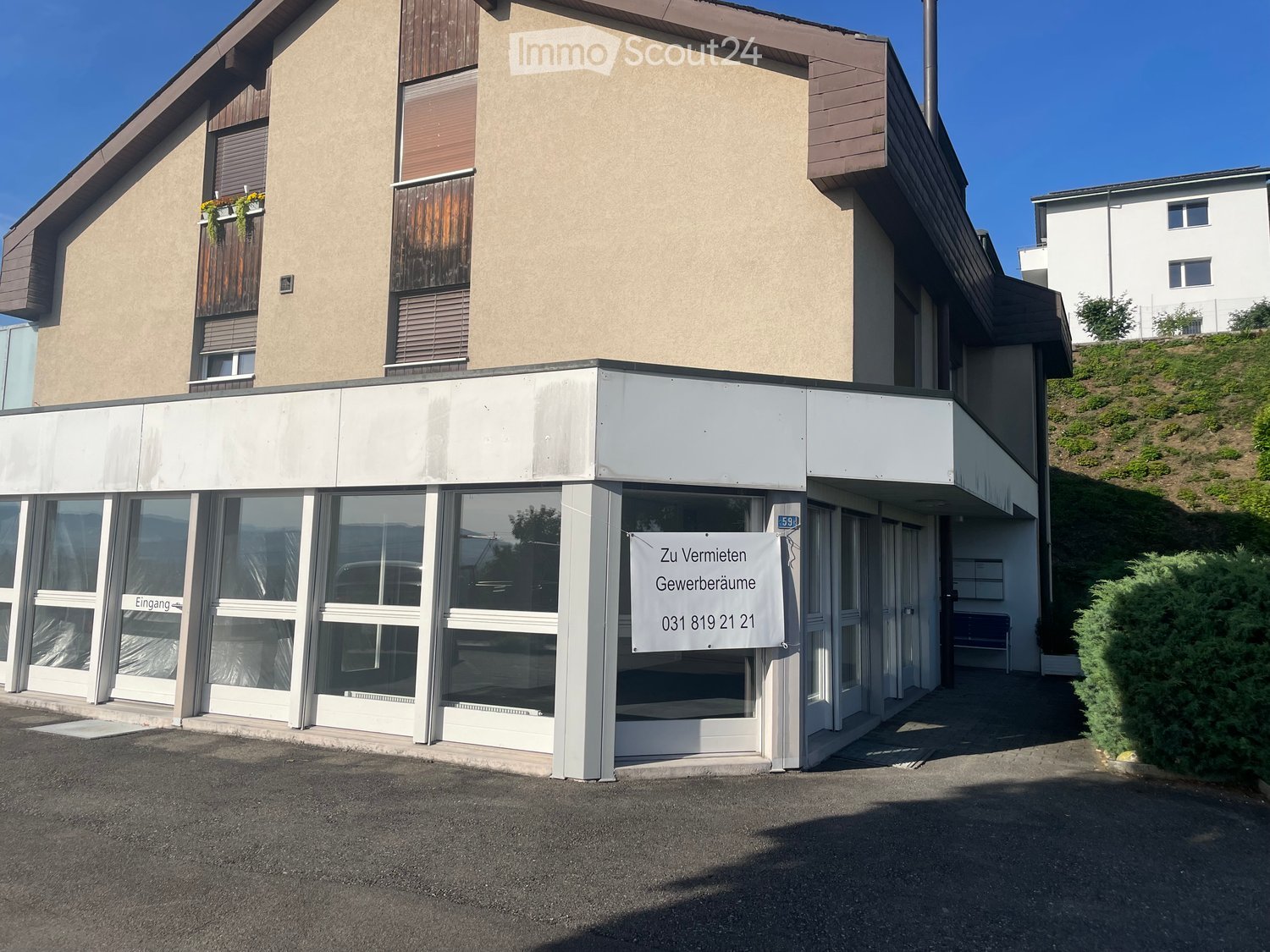 Two-story building with a modern facade, large windows, and a sign advertising commercial space for rent.