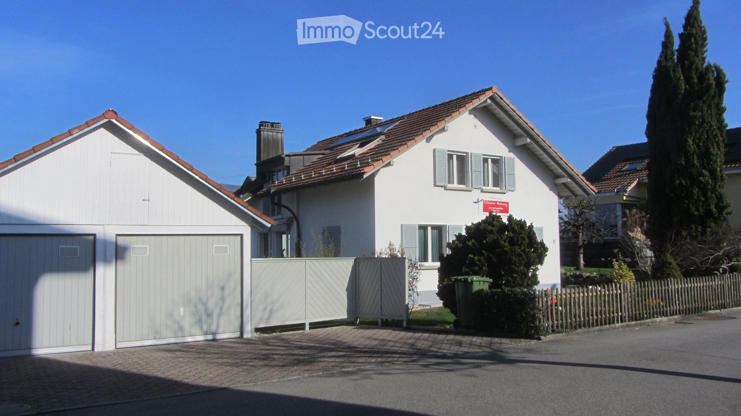 2 story house, white exterior, brown roof, 2 garages, solar panels, fence, trees