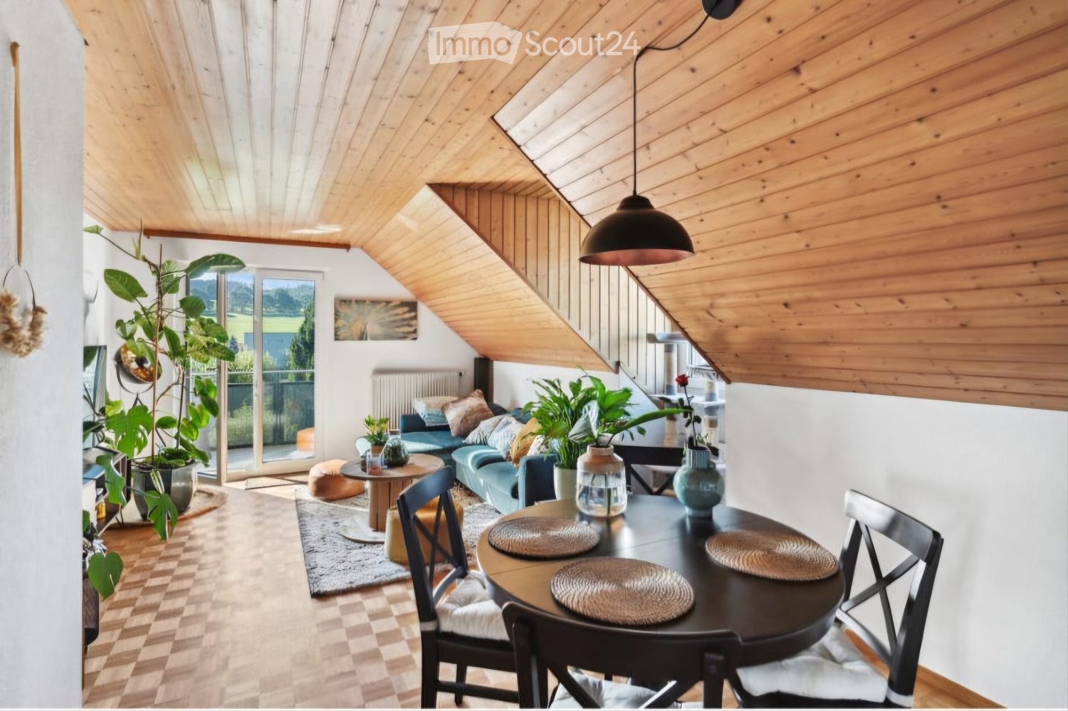 Modern living and dining area with wooden ceiling, pendant light, sofa, coffee table, dining table, chairs, and plants.