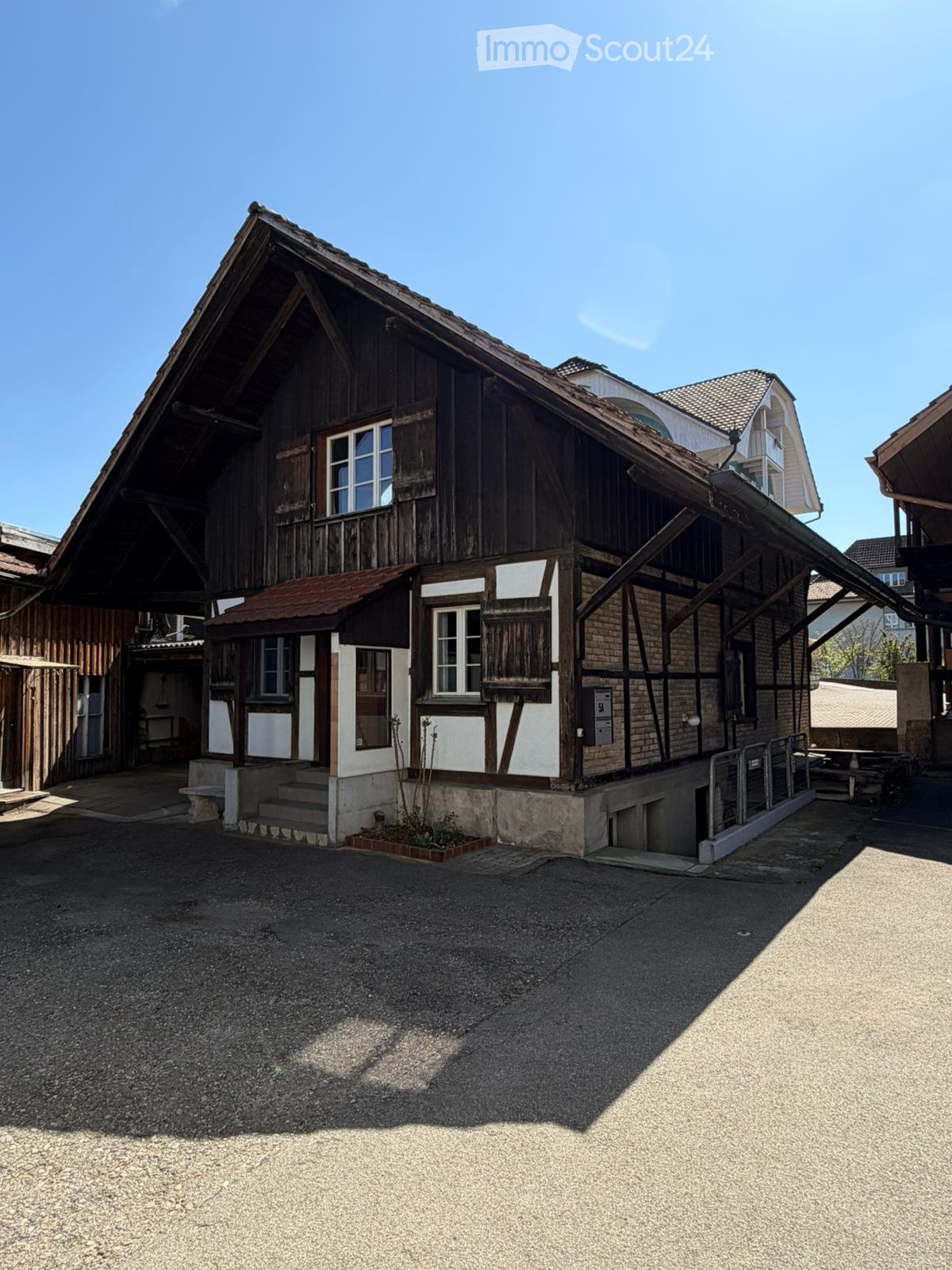 Traditional wooden building with a steep roof, white-painted sections, and a small porch with steps leading up to it.