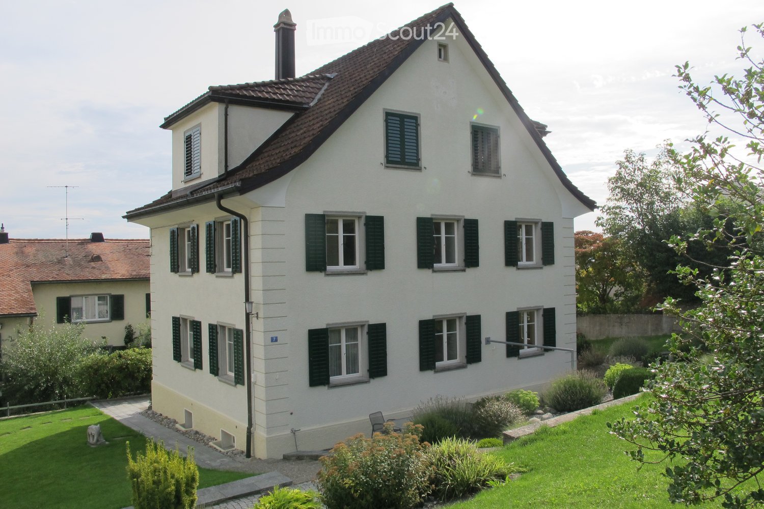 3 story house, white exterior, brown roof, green shutters, garden, pathway