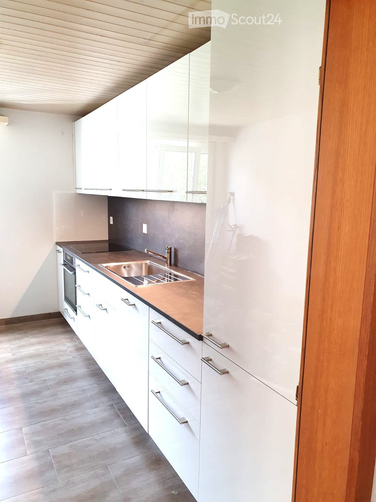 Modern kitchen with white cabinets, stainless steel sink, and copper countertop.