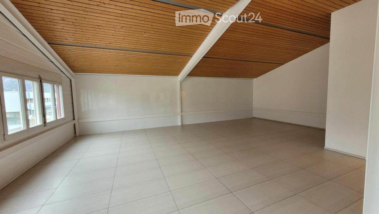 Empty room with white tiled floor, white walls, and wooden slatted ceiling. Three windows on one side provide natural light.