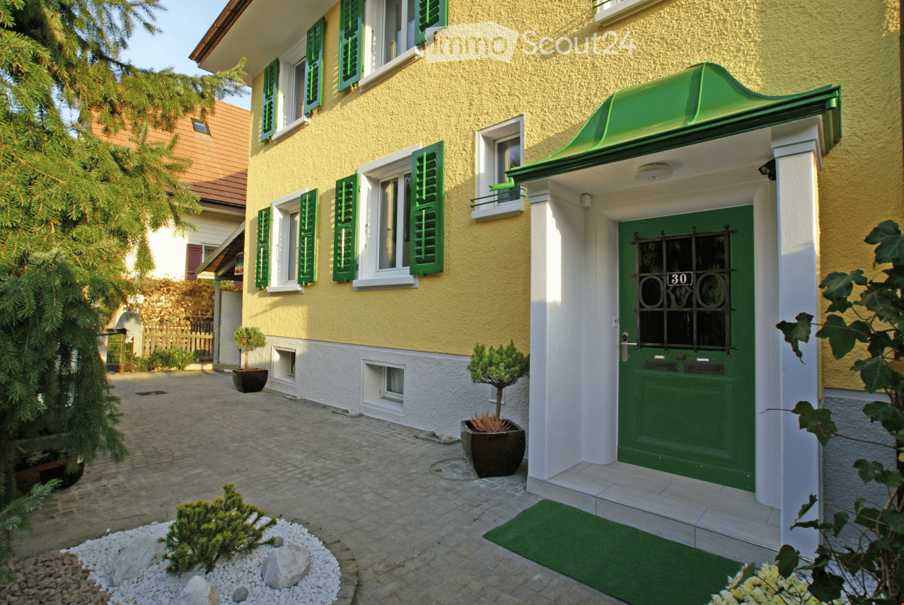 yellow house, green shutters, green door, green roof, brick driveway, potted plants