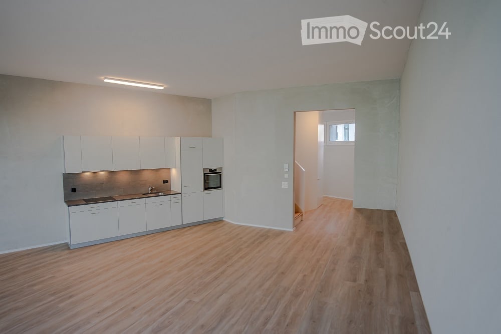 empty kitchen with built-in appliances, white cupboards, wooden floor