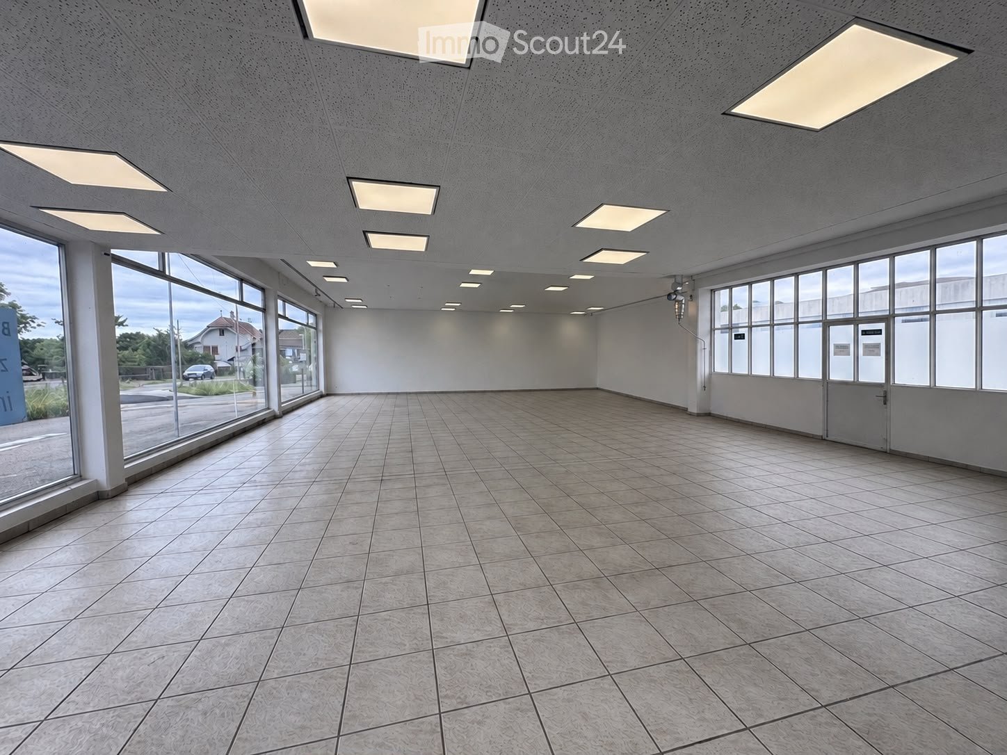 Empty room with tiled floor, large windows, and recessed lighting. No furniture or equipment present.