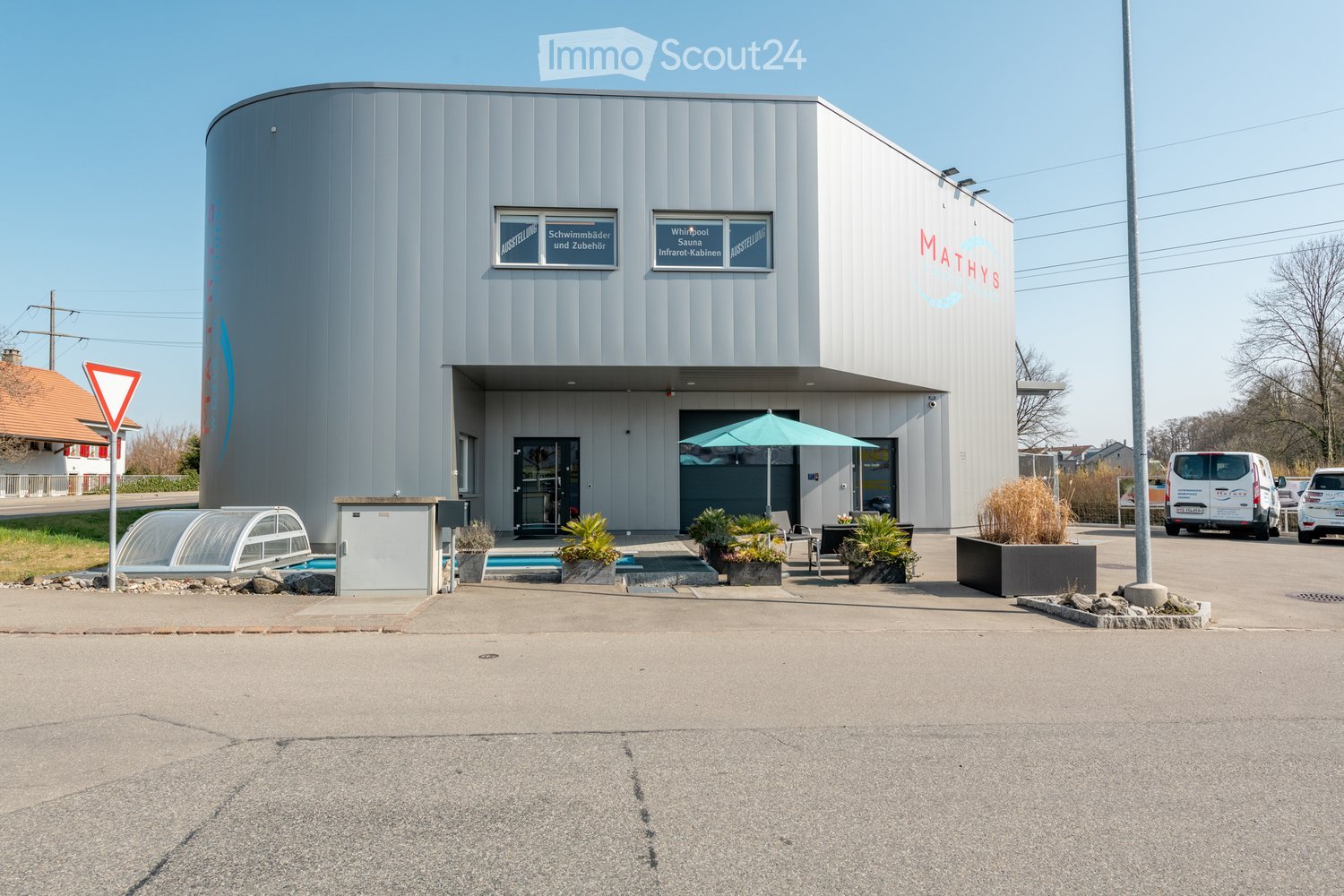 Modern building with a swimming pool area, outdoor seating, and signage for a wellness center.