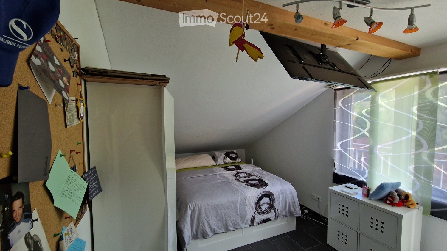 sloped ceiling, bed, bedside table, window, wardrobe, bulletin board, mounted television, pin cushion