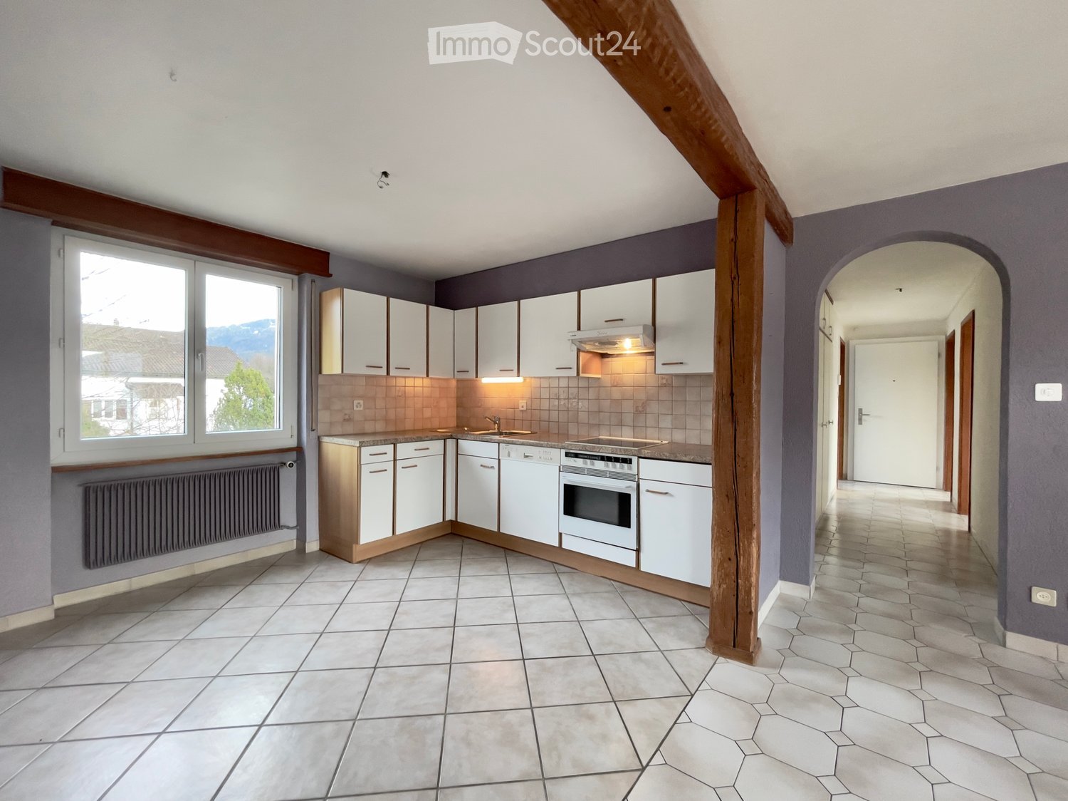 modern kitchen with white tiles, white cabinets, white appliances, large window, tiled wall, wooden beam, wooden pillar