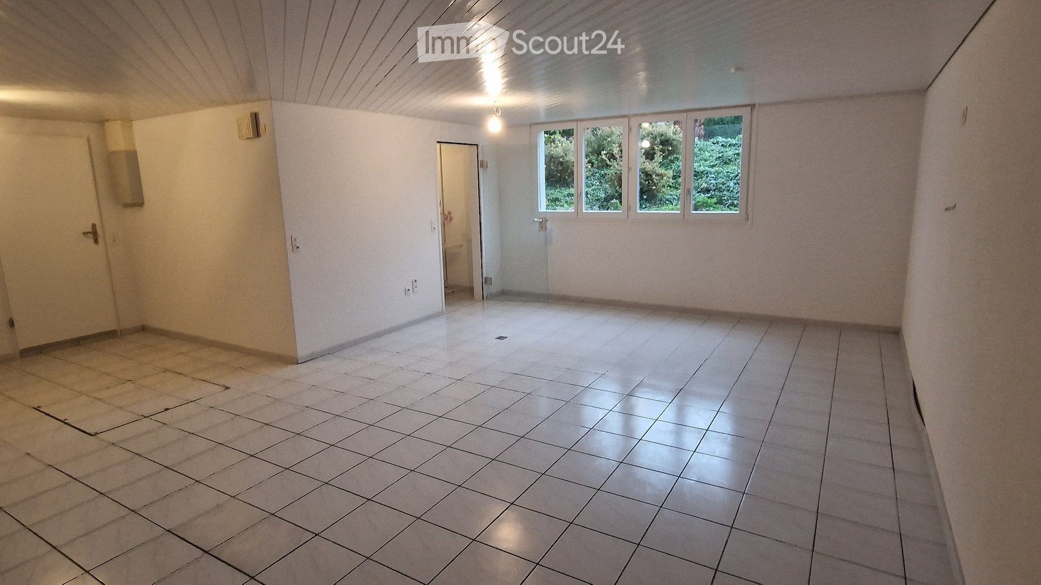 Empty room, white tile floor, three windows, open door leading to a toilet.