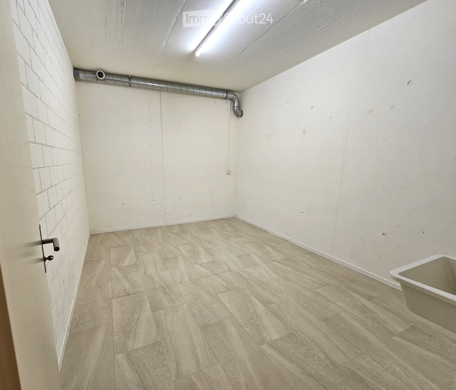 Empty bathroom with tiled floor, white walls, and a single bathtub in the corner.